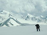 Руководитель попой к верху и под рюкзаком прощупывает закрытый ледник на предмет трещин. На фоне гор